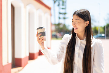 Pretty Chinese woman holding a take away coffee at outdoors with happy expression