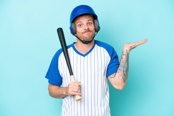 Baseball player with helmet and bat isolated on blue background having doubts while raising hands