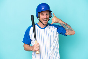 Baseball player with helmet and bat isolated on blue background making phone gesture. Call me back sign