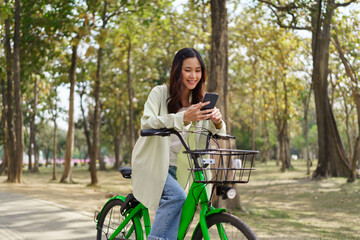 Fototapeta na wymiar Women using smartphone to chatting and surfing social media after cycling for exercise in the park