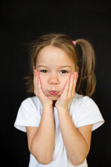 funny little girl making faces on a dark background