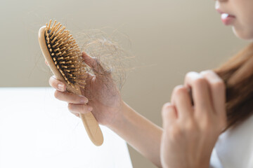Close-up young woman brushing her hair and have many hair loss on the comb