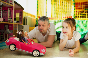 a happy dad with a little daughter frolics in a children's play center