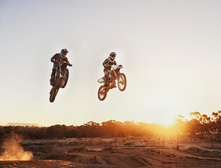 Adventure, speed and motorbike for a competition during a race outdoor for extreme sports. Action, men and motorcycle on racetrack for sport jump on fast transportation in the dirt with sunset.