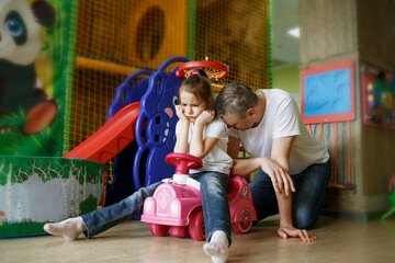 father and daughter are tired and sad sitting in the children's play center
