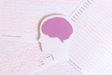 Brain paper cutout on background of brain waves from electroencephalography. Autism, epilepsy and...