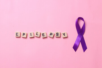 Purple ribbon with epilepsy lettering on blocks isolated on pink background. 