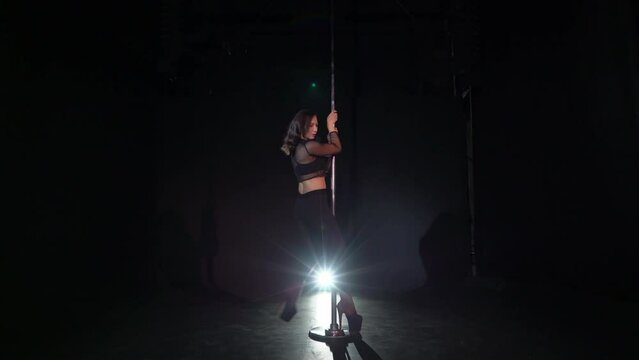 Pole dance. Young beautiful caucasian brunette woman dancer in studio.