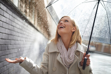 Smile, excited woman and rain in the city with umbrella, freedom and happiness on holiday. Winter...