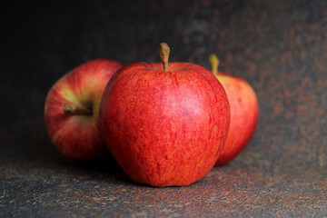 Three red apples on a dark background