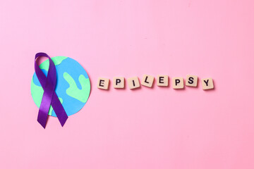 Epilepsy lettering on cubes with purple ribbon on globes isolated on pink background. World epilepsy day. 
