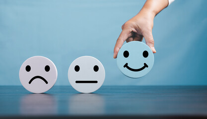 Woman hand holding happy face smile face icon on round blue object. Customer experience and service...