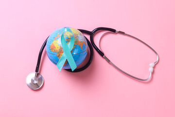 Teal awareness ribbon on globe with stethoscope over pink background. Female reproductive health concept. World Ovarian Cancer Month. 