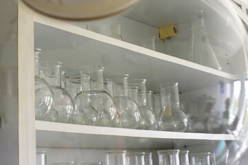 Empty clean laboratory glassware.many flasks on the shelves of wall cabinets