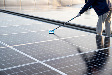 Asian male worker or engineer in solar power plant The solar panel is being cleaned using a mop to...