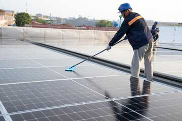 Asian male worker or engineer in solar power plant The solar panel is being cleaned using a mop to clean it. at the solar power station