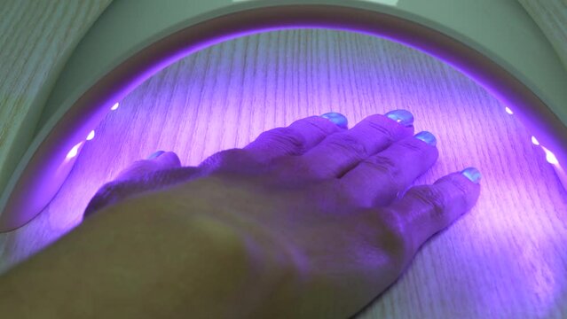 A hand with manicure after applying a top coat, curing process in led lamp