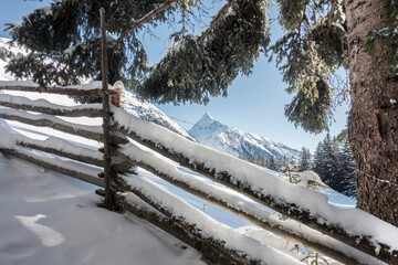 Holzzaun am Wanderweg in einer verschneiten Winterlandschaft im tiroler Zillertal