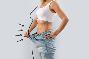 Cropped of slender woman wearing oversize jeans, showing thin waist