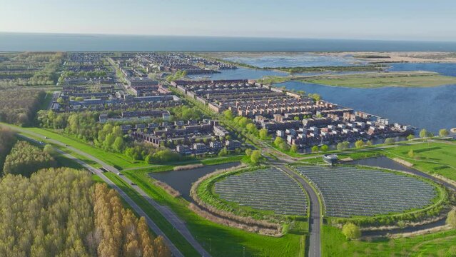 The Almere neighborhood is a modern and sustainable community that utilizes a solar panel island Zoneiland to partially power its district city heating system. Aerial video.