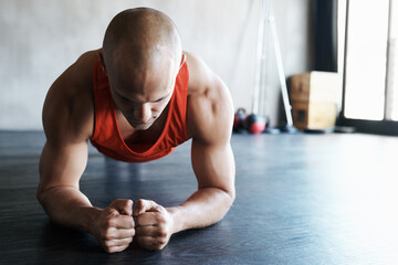 Gym, focus and man doing floor plank exercise, health performance or core strength building for bodybuilding. Training, commitment and person concentrate on fitness, muscle development or workout