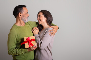 Satisfied caucasian old husband hugging woman gives gift, congratulations with holiday, enjoy anniversary