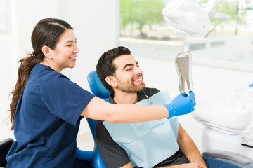 Satisfied patient looking at his white healthy teeth at the dentist