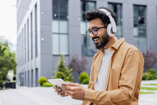 A young Inus man walks around the city in headphones, a businessman in a shirt watches an online video stream using a tablet computer, a programmer in a shirt outside an office building.