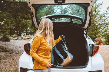 Woman puts backpack in a car trunk road trop vacations travel active lifestyle outdoor rental auto