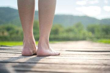 Close-up at woman barefoot is standing on wooden plank board floor with background of rice paddy agriculture field, relaxation activity concept scene. 