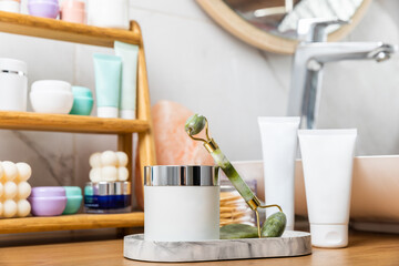 Care cosmetics on the shelf in the bathroom. Cosmetic tube. Cleanser, face and body cream, face roller and gua sha, tonic. Shelf with cosmetics in the interior of the bathroom.Beauty concept.