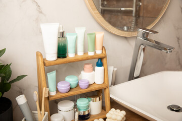 Care cosmetics on the shelf in the bathroom. Cosmetic tube. Cleanser, face and body cream, face roller and gua sha, tonic. Shelf with cosmetics in the interior of the bathroom.Beauty concept.