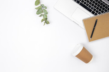 White background with laptop, notepad and disposable glass, top view.