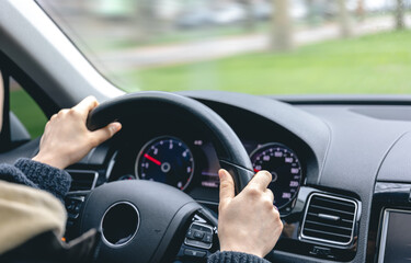 Woman driver's hands on a car steering wheel.
