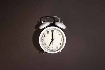 White alarm clock on a brown background, top view.