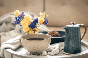 Home composition with a cup of tea and flowers on a blurred background.