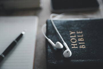 Christian online technology concept. Earphones over the holy bible with digital smartphone, Online...