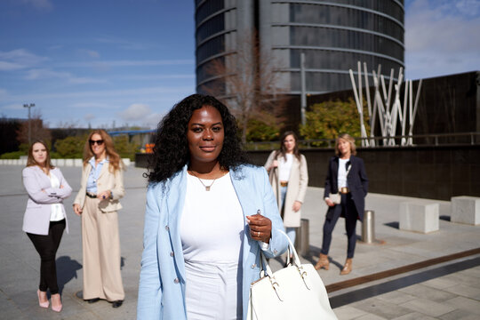 African American business woman looking at camera while standing in front of her business team outdoors. Business concept.