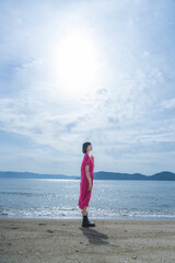 Fototapeta na wymiar 海岸を散策するワンピースの女性