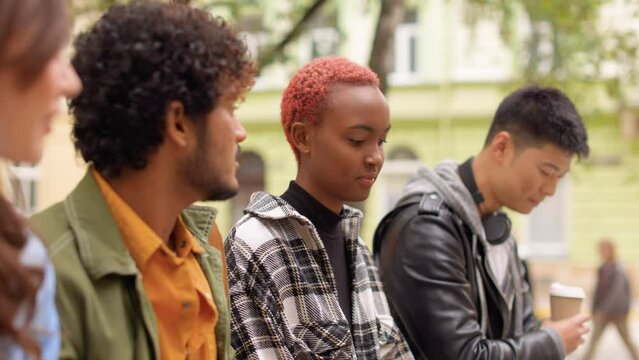Close up of young beautiful multi-ethnic people speaking outdoors. Diverse multiracial male and female friends having conversation on street. Friendship, communication, leisure time, youth concept