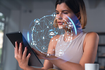 Smiling businesswoman in casual wear holding tablet device touching it at office workplace. Concept of distant work, business education, information technology. Social network abstract hologram