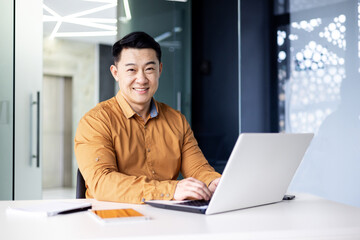 Successful asian businessman smiling and looking at camera, programmer porter inside office using...