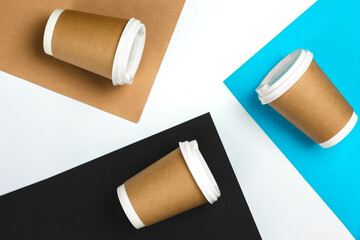 Paper cups on colored paper background, top view.