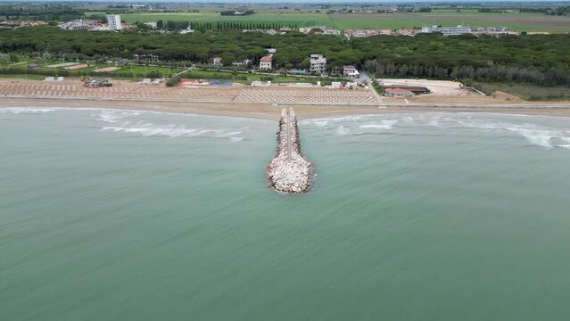 Smooth sea with beach and leaden rocks. Late spring, cloudy skies and rain to come. Italy, Veneto, shore of Eraclea