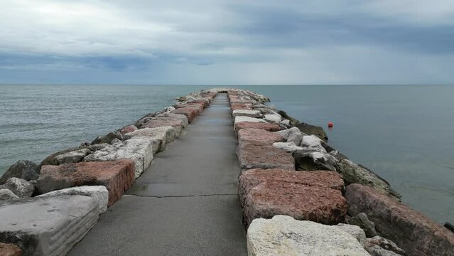 Smooth sea with beach and leaden rocks. Late spring, cloudy skies and rain to come. Italy, Veneto, shore of Eraclea