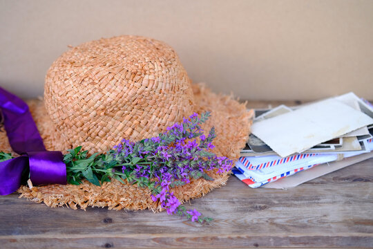 straw hat, old photographs, home archive, letter, bouquet of purple wildflowers on old wooden table, nostalgia, past love, bunch of wild flowers, concept of genealogy, memory of ancestors, family tree
