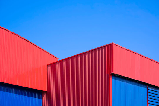 Red and blue Corrugated metal Warehouse Buildings in modern style against blue sky background