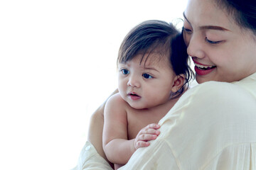 Happy smiling toddle baby on mother shoulder on white background, mom holding and hugging little cute daughter kid, child girl in embrace of parent, love in family, childhood care and motherhood.