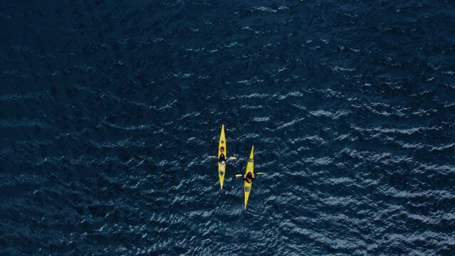 Top view on two bright yellow single kayaks floating in deep blue ocean water in Norwegian fjord. Epic and inspiring active lifestyle adventure concept and idea. Sport healthy exploring of nature