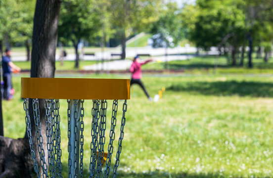 Disc golf player throwing a flying disc in the public park